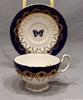 Teacup and saucer set showing the cobalt blue and gold ornate detailing with butterfly on saucer center
