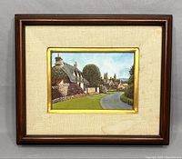 Framed oil painting by Eugene Schmidt depicting a European village with thatched roofs and stone walls along a winding road.