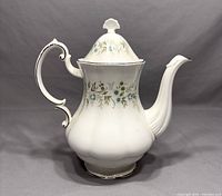 Front view of coffee pot with lid showing floral design and gold trim on white porcelain.