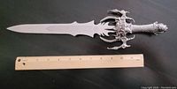 Full view of the silver collectible dagger with demon claw handle and ruler for scale showing about 39 cm length.