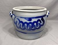 Front perspective view of salt glaze stoneware planter, showing blue hand-painted designs and left handle