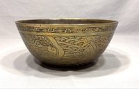 Side view of the vintage Chinese brass bowl showing detailed etched designs and geometric border along the rim.