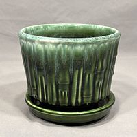 Front view of green McCoy pottery planter with matching saucer, showing textured vertical ribbing and glossy glaze.