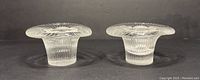 Front view of both clear glass art candle holders side by side, showing ribbed texture and flared top edges.