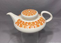 Front and top view of the white ceramic Ridgway Christina teapot with orange decorative pattern on body and lid.