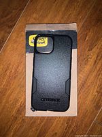 Black OtterBox protective phone case lying on cardboard packaging with OtterBox label visible.