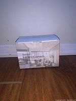 Closed product box labeled 'Smart Battery Camera' showing branding and room interior image on front.