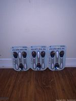 Three unopened packages of My First Meal Pal toddler spoons, each containing two spoons with soft colorful handles and silver spoon heads.