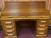 Front view of closed roll top desk showing oak wood, drawers, and roll top