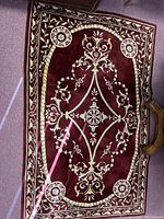 Full view of Asian area rug showing central medallion and floral patterns on burgundy background.