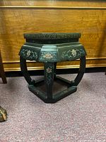 Side view showing the black lacquer finish, curved legs, and floral painted accents on the structure