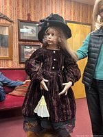 Front view of the porcelain doll showing detailed velvet dress, hair, and face.