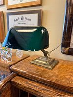 Front view of Emeralite desk lamp showing green cased glass shade and brass base on wooden surface.