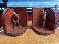 Front view of both bookends showing golfers in putting and swinging poses inside vintage style book shapes with textured brown exterior