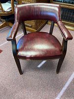 Front view showing leather seat, backrest, armrests, and nailhead trim with wood legs.