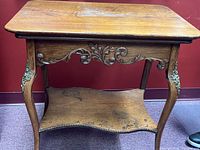 Front view of the oak end table showing carved apron and lower shelf details.