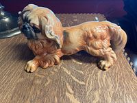 Side angle photo of the Pekingese ceramic dog figurine showing glossy warm brown fur and detailed sculpting.