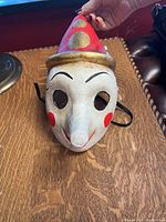 Front view of the white Venetian Pinocchio mask showing facial features and hat