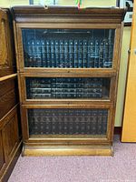 Front view of first oak barrister bookcase with three glass-fronted sections filled with books