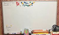 Full front view of large magnetic whiteboard with colorful magnets, markers, eraser and cleaning spray on ledge