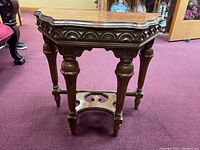 Frontal angle view of the wooden side table showing ornate carved apron and legs.