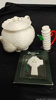 Lot showing three items: Godinger teapot, Fitz and Floyd Leaning Tower of Pisa creamer, and boxed Donegal by Belleek Christmas ornament