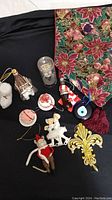 Entire lot displayed on black fabric background featuring various Christmas ornaments, bottle stopper, and table runner with poinsettia design