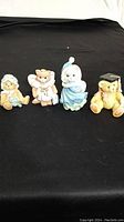 Front view of all four teddy bear figurines arranged on black fabric