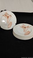 Six stacked Fitz and Floyd ceramic plates with brown seashell design on white.