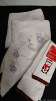 Photo of white cotton towels with holiday embroidery including ornaments and a penguin.
