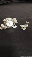 Photo showing both pewter desk charms: one with a clock and owls, the other a single owl figurine with blue accent.