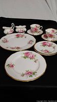 Full china set arranged showing dinner plate, bread plates, salad plate, cups, saucers, cream, and sugar.