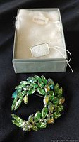 Full view of the Sherman brooch with pale lime green rhinestones in a circular wreath design, displayed in original Eatons box with tag.