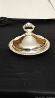 Closed covered dish showing ornate handle and ribbed edge detail