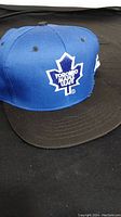 Side view of blue and black Starter snapback cap with Toronto Maple Leafs logo embroidered on front.