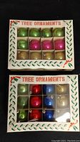 Two boxes of miniature Christmas tree ornaments visible through transparent panel with arrangement and packaging