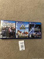 Three PS4 game cases displayed closed on carpet: Marvel Avengers, Pixark, and Star Wars Battlefront II.