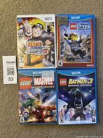 Four video game cases showing front cover art of the 3 WiiU LEGO games and 1 Wii Naruto game.