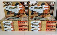 Eight brand new Nerf Ultra AMP blasters stacked in two piles, all still sealed in original packaging.