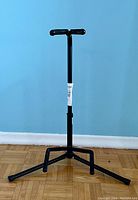 Full view front image of black adjusted guitar stand with rubber padded top support arms and tripod base.