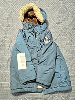 Blue boys winter jacket with hood and faux fur lining visible, tag showing size 6.