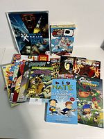 Group display of multiple kids books including Scooby Doo comics, superhero comics, Big Nate, Ricky Ricotta series, and more arranged on white surface.