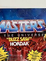 Close-up of the Masters of the Universe Buzz Saw Hordak packaging showing the name and comic inclusion details.