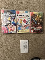 Photo showing three Nintendo Switch games: CN Battle Crashers!, Snipperclips Plus Cut it Out Together!, and Hyrule Warriors Age of Calamity, arranged on carpet with MaxSold auction tag.