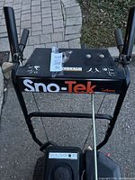 View of control panel displaying Sno-Tek branding on black steel handle assembly