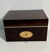 Front view of the closed mahogany wooden letterbox with decorative inlay and gold-tone horizontal band.