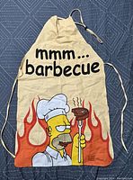 Full front view of apron showing entire Homer Simpson BBQ design with text and flames.