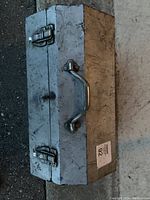 Closed metal toolbox showing latch locks and handle on top