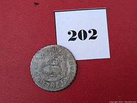 Oblique photo of the coin on red background with lot number card