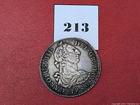 General obverse view of the coin on red background with lot number card '213' visible.